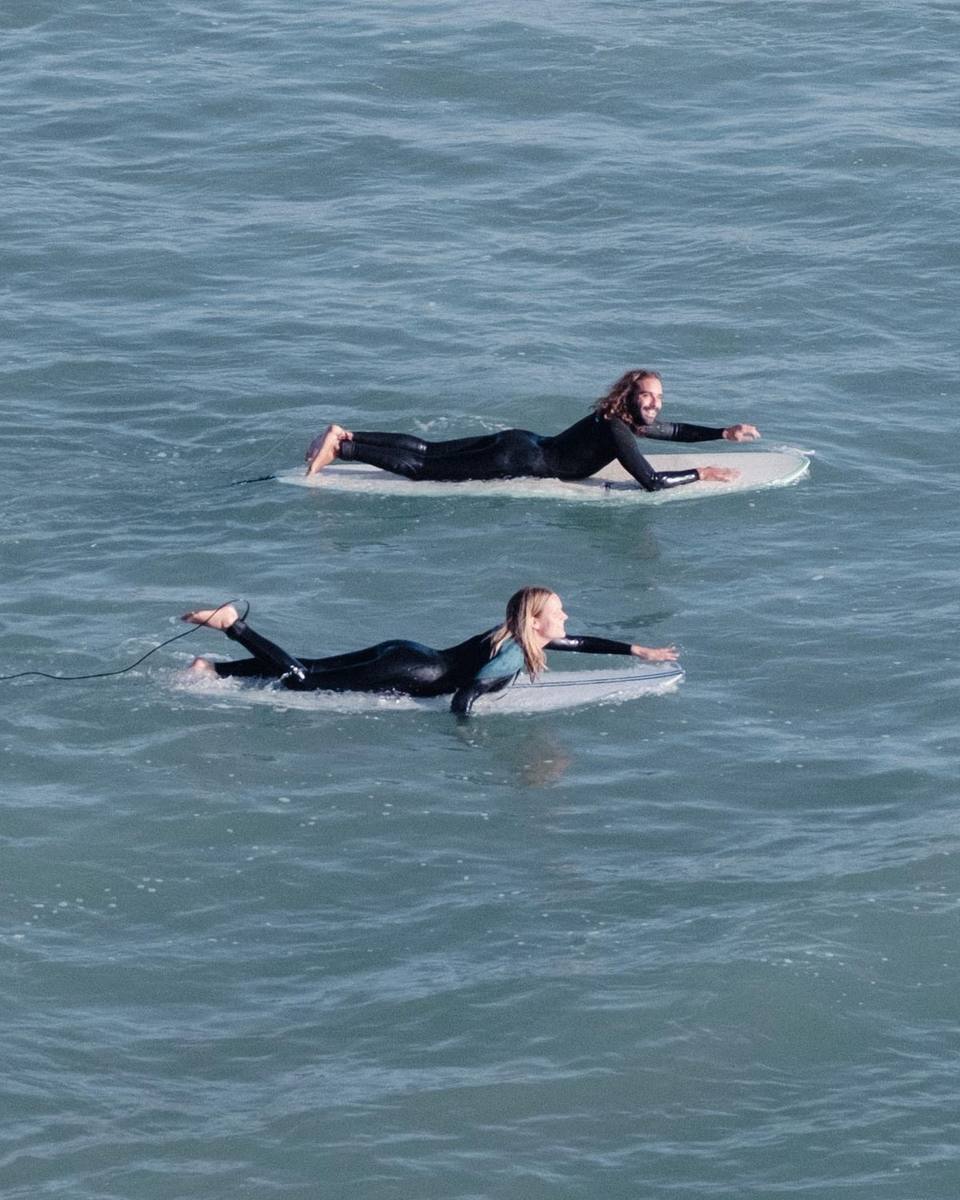 Instructor and student paddling side by side, smiling, in calm blue water