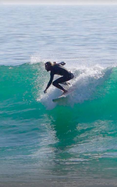 Surfer turning on a green wave, spray coming off the top