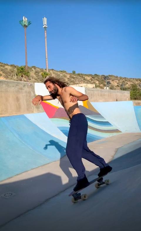 Surf skater carving down a painted ramp under a blue sky