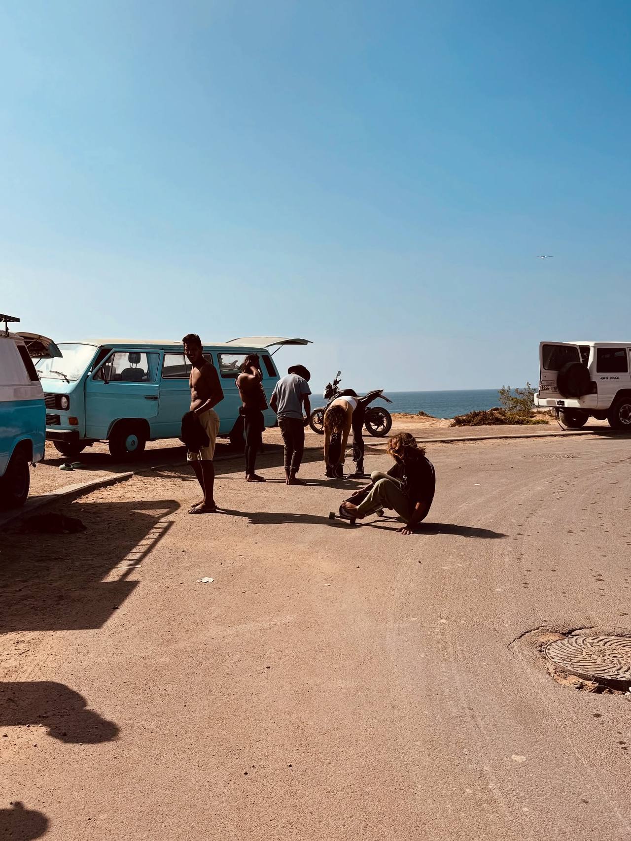 Friends getting changed by the vans after a surf, the sea behind them
