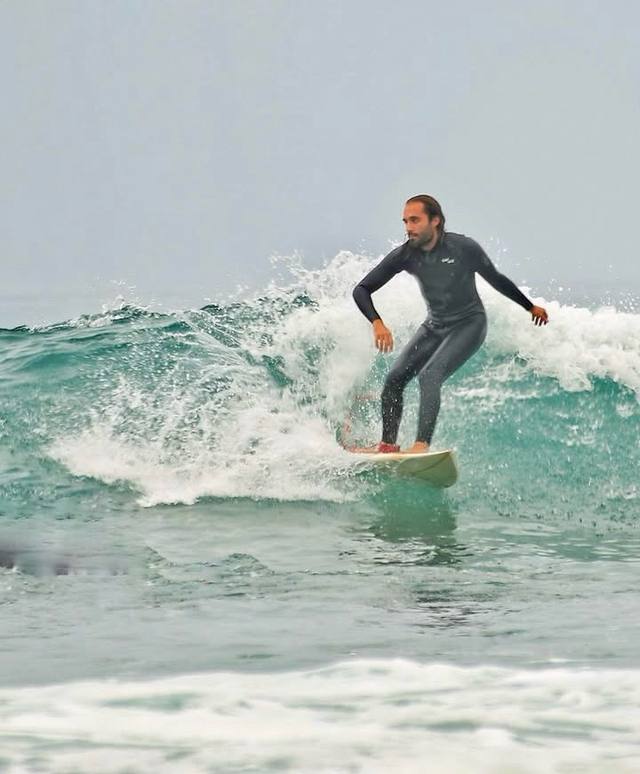 Surfer turning on a small wave in the morning mist