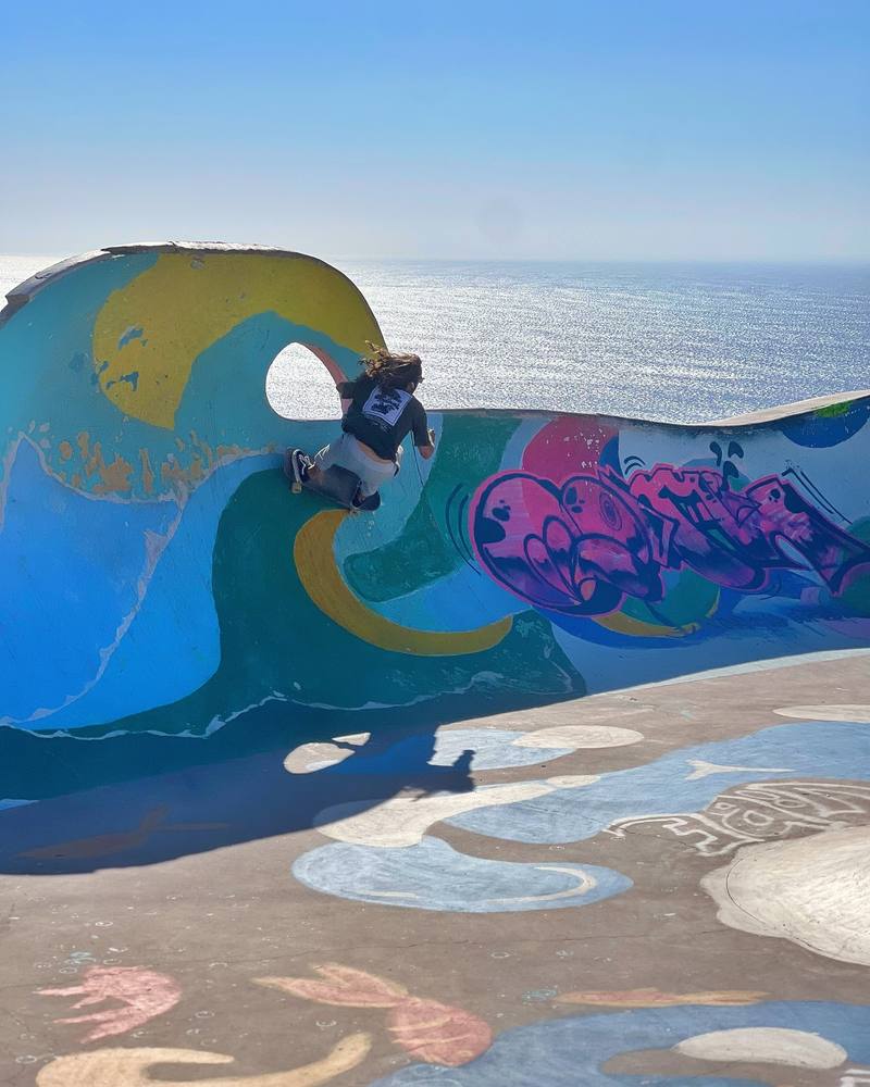 Surfer practising turns on a surf skate along a painted wave, the ocean behind