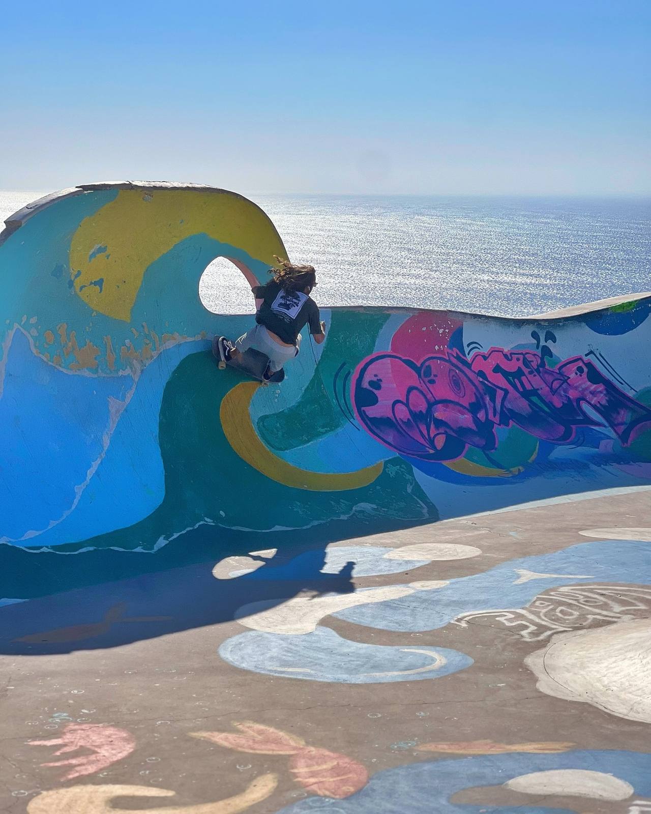 Surfer practising turns on a surf skate along a painted wave, the ocean behind
