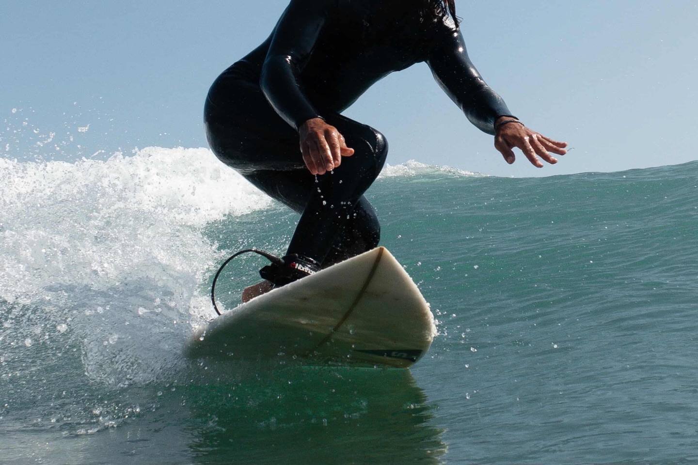 Surfer in a wetsuit turning on a green wave, spray flying off the board, in Morocco